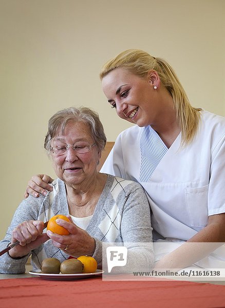 Nurse helping a senior citizen to peel fruit  Germany  Europe