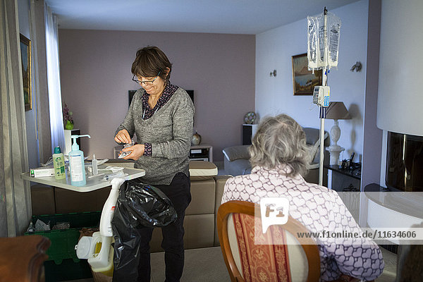 Reportage über einen häuslichen Pflegedienst in Savoie  Frankreich. Eine Krankenschwester wechselt bei einem Krebspatienten den Beutel für parenterale Ernährung.