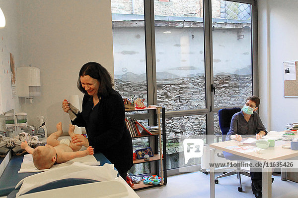 Reportage in einem französischen Mütter- und Kinderschutzzentrum in Châteaubriant  Frankreich. Konsultation mit einem Kinderarzt. Entkleiden des Kindes.