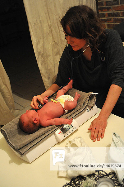 Reportage aus der Praxis einer freiberuflichen Hebamme in Ham  in der Region Somme  Frankreich  bei Hausbesuchen. Besuch nach der Entbindung: Die Hebamme untersucht das Neugeborene.