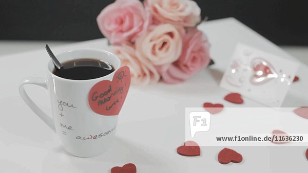 Kaffeetasse mit herzförmigem Aufkleber  Herzen und Blumen auf Tisch 2