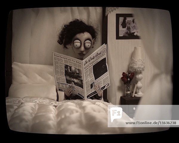Puppenfigur eines Zeitung lesenden Mannes im Bett  Stop-Motion-Effekt