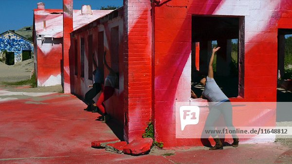 Drei moderne Tänzer tanzen gegen ein rotes Gebäude während einer Probe