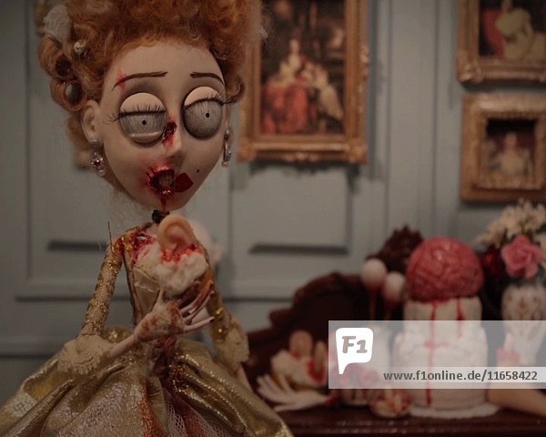 Groteske Puppenfiguren von Zombie Marie Antoinette  die in einen blutigen Cupcake beißt  während zwei entsetzte Menschen zusehen  Stop-Motion-Effekt