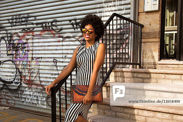 Junge weibliche Mode-Bloggerin mit Afro-Haaren auf Stadttreppe  New York  USA