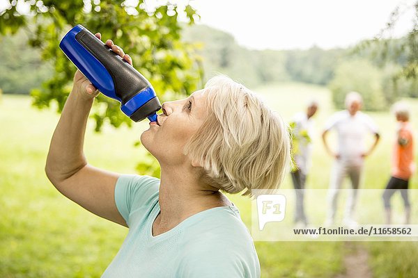 Ältere Frau trinkt Wasser aus Sportflasche..
