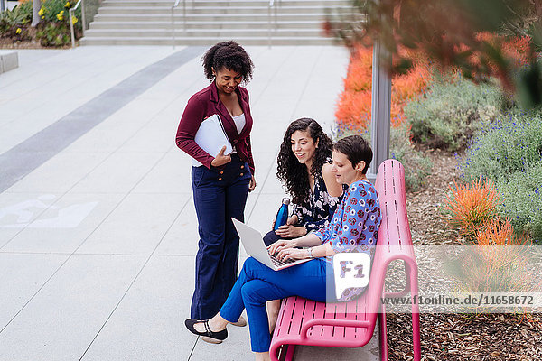 Drei Frauen im Freien  die sich einen Laptop anschauen