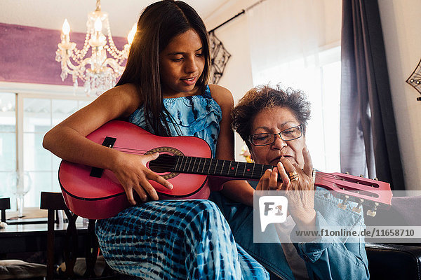 Grandmother teaching granddaughter to play guitar