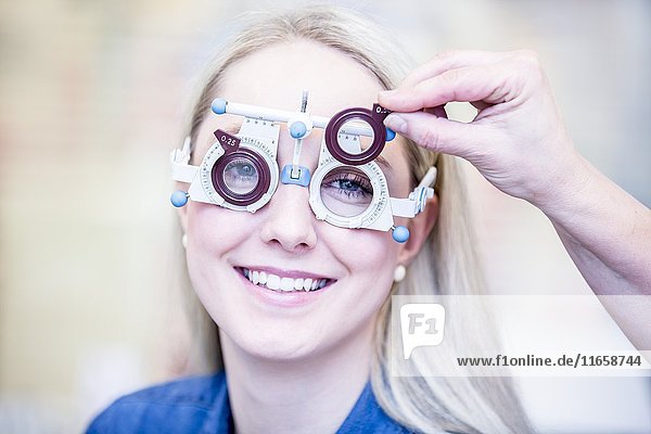 Portrait of cheerful young woman having eye examination in optometrist's shop  close-up.