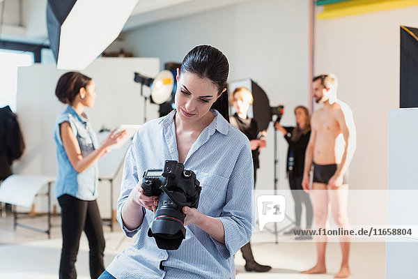 Junge Fotografin bespricht Aufnahme mit digitaler Spiegelreflexkamera im Fotostudio