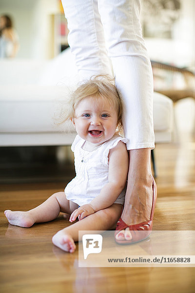 Porträt eines kleinen Mädchens  das auf dem Boden zwischen den Beinen der Mutter sitzt