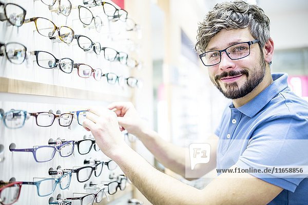 Mann in der Nähe eines Brillengestells in einem Optikergeschäft.