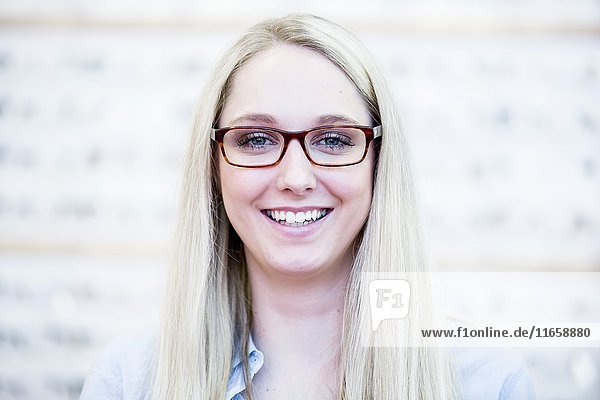 Porträt einer Frau,  die in einem Optikergeschäft eine Brille ausprobiert.