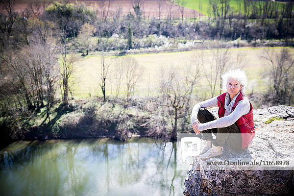 Frau sitzt auf einem Felsen und schaut lächelnd in die Kamera  Bruniquel  Frankreich
