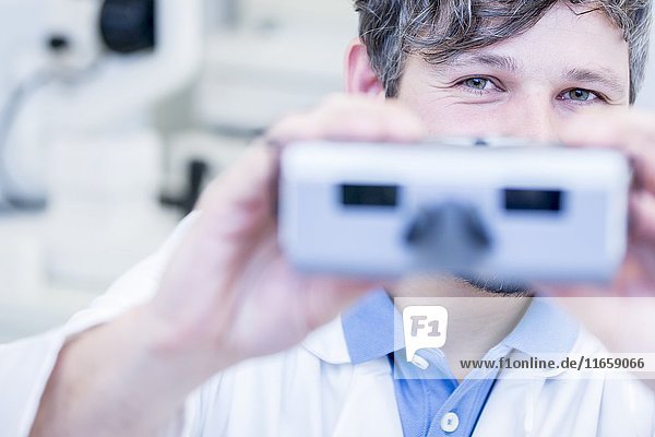 Porträt eines Optometristen  der einen Sehtest mit einem Sehtestgerät in einem Optikergeschäft durchführt.