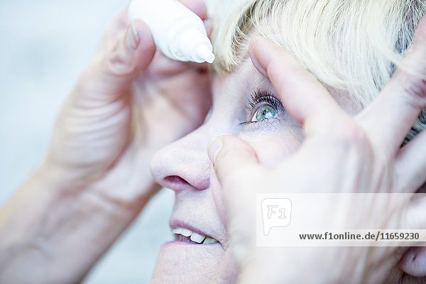 Close-up of person applying eye drops.