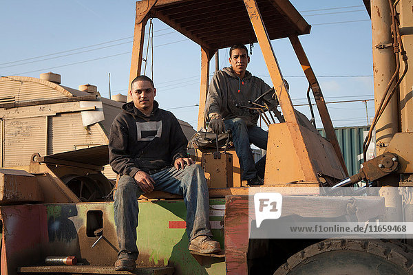 Kollegen auf der Baustelle auf schweren Maschinen sitzend