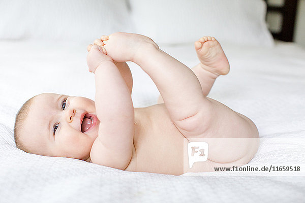 Portrait of happy naked baby girl on bed