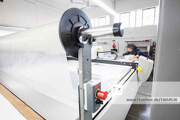 Fabrikarbeiterin  die in einer Bekleidungsfabrik an einer Musterschneidemaschine arbeitet