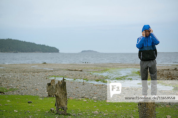Teenager  der auf einem Baumstumpf steht  Pacific Rim National Park  Vancouver Island  Kanada