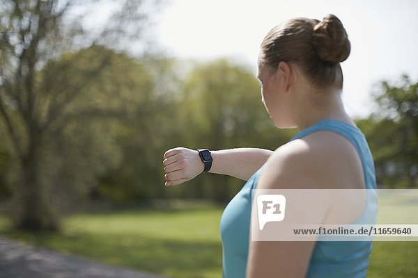 Young woman checking sports watch.