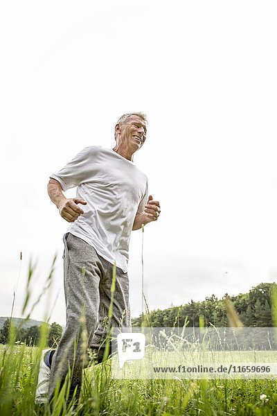 Älterer Mann joggt im Gras.