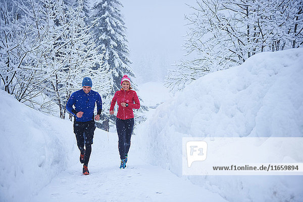 Female and male runners running in falling snow  Gstaad  Switzerland