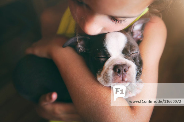 Girl hugging Boston Terrier puppy