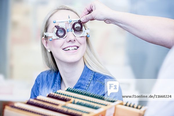Fröhliche junge Frau bei einer Augenuntersuchung in einem Optikergeschäft,  Nahaufnahme.