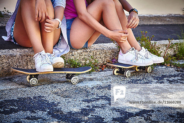 Zwei Freundinnen  Entspannung im Freien  Füße auf Skateboards ausruhen  niedriger Abschnitt
