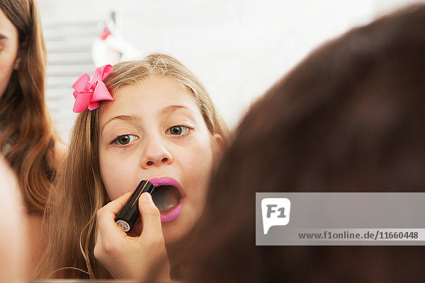 Girls applying makeup in mirror
