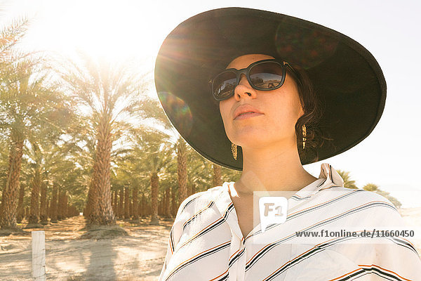 Porträt einer Frau mit Sonnenbrille und Sonnenhut beim Wegschauen  Palm Springs  Kalifornien  USA