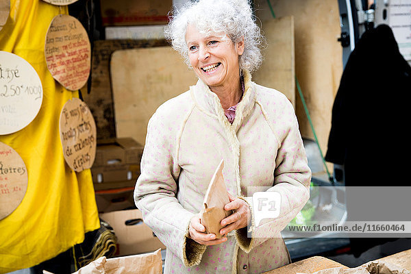 Ältere weibliche Standinhaberin verkauft getrocknete Lebensmittel auf dem lokalen französischen Markt