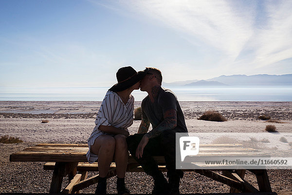 Couple sitting on picnic bench kissing  Salton Sea  California  USA