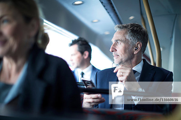 Geschäftsmann hört Smartphone-Kopfhörer im Doppeldeckerbus