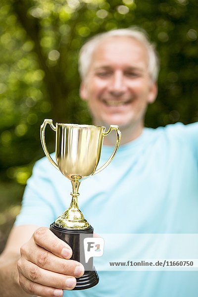 Mature man holding a trophy.