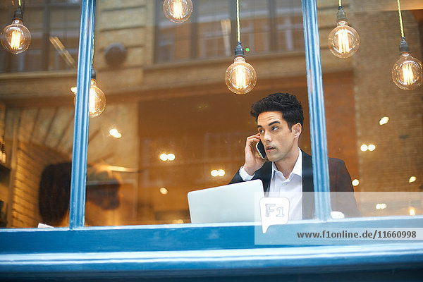 Fensteransicht eines Geschäftsmannes  der im Cafe telefoniert