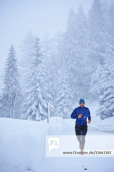 Männlicher Läufer läuft bei Schneefall  Gstaad  Schweiz