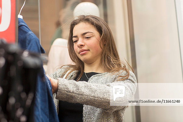 Junge Frau betrachtet Jeansjacke am Marktstand