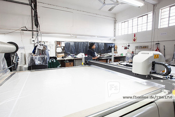 Musterschneidemaschine und Fabrikarbeiter in Bekleidungsfabrik