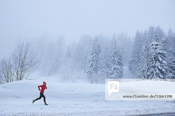 Distant view of female runner running in deep snow  Gstaad  Switzerland