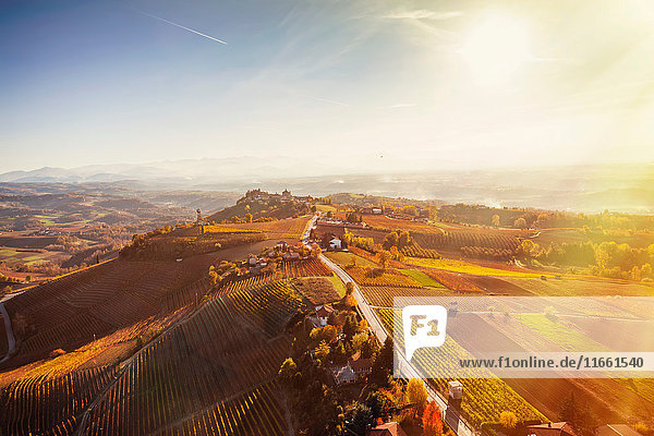 Sonniger Blick aus dem Heißluftballon auf eine hügelige Landschaft und herbstliche Weinberge  Langhe  Piemont  Italien