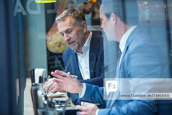 Zwei Geschäftsleute diskutieren im Restaurant am Fensterplatz