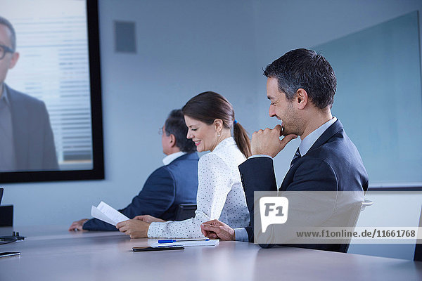Businesswoman and man smirking during office conference call