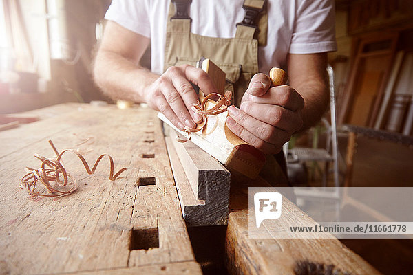 Mittelschnitt eines männlichen Zimmermanns mit Holzhobel an der Werkbank