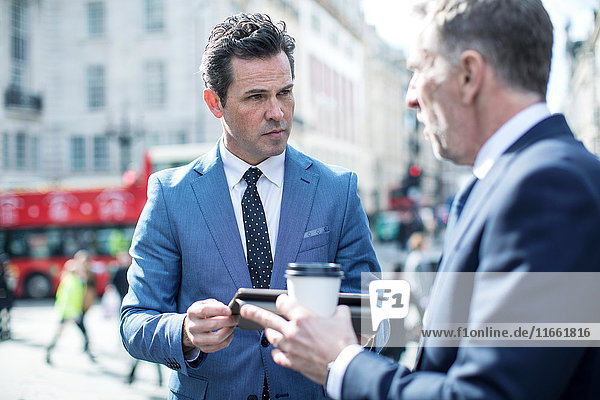 Businessmen in street using digital tablet  London  UK