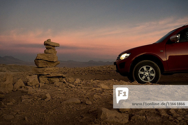 Car by stack of balanced rocks at sunset San Pedro de Atacama Chile
