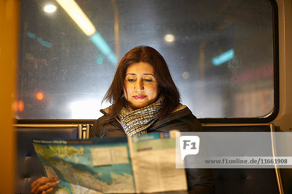 Im Bus reisende Frau schaut auf Karte