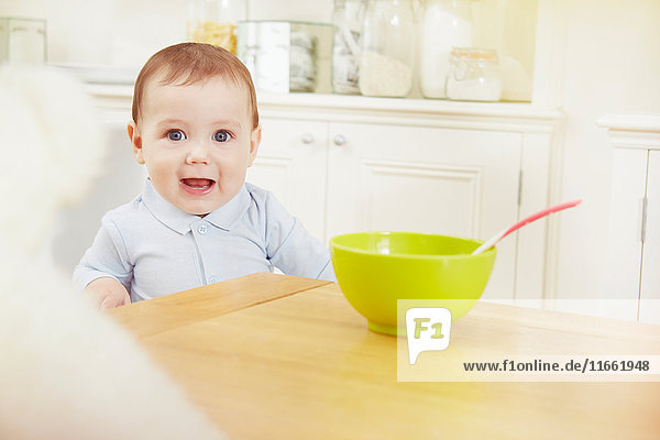 Portrait of baby boy with breakfast bowl on table