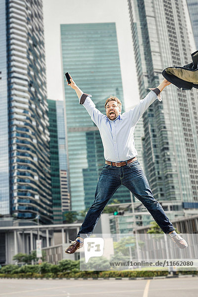 Happy businessman jumping for joy by city skyscrapers